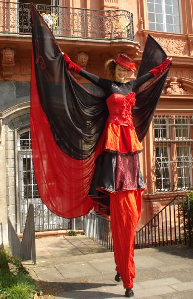 eleganter Stelzen Walkact mit rot schwarzem Kostüm